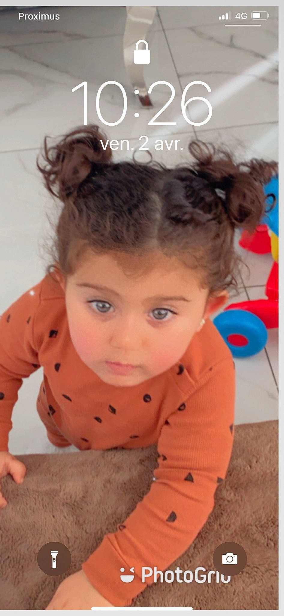 Camélia a rejoint le concours — aidez-le/la à gagner de superbes lots ! baby_toddler_clothing, blond, brown_hair, cheek, child, eyebrow, eyelash, flooring, fun, hair, happy, head, iris, neck, nose, person, sitting, skin, sleeve, toddler