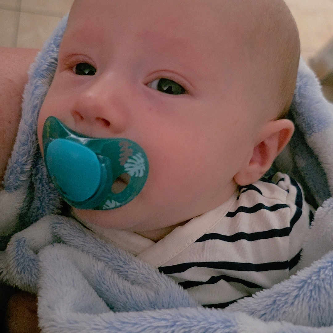 Maël participe au concours pour gagner de l'argent avec cette photo : baby, blanket, calm, child, close_up, comfort, cute, face, head, indoor, infant, newborn, pacifier, person, skin, sleepy, soft_texture, striped_clothing, wrapped, young