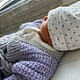 newborn, baby, knitted_sweater, purple, hat, stars, sleeping, window, natural_light, soft_texture, closeup, infant, cozy, warm_clothing, peaceful, side_profile, person, child, cuteness, indoors
