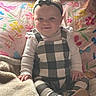 Aries is registered to the contest to win money with this photo: baby, child, smiling, sitting, bed, pillow, blanket, clothing, headband, face, indoor, cute, happy, infant, patterned, footwear, person, portrait, soft, cozy