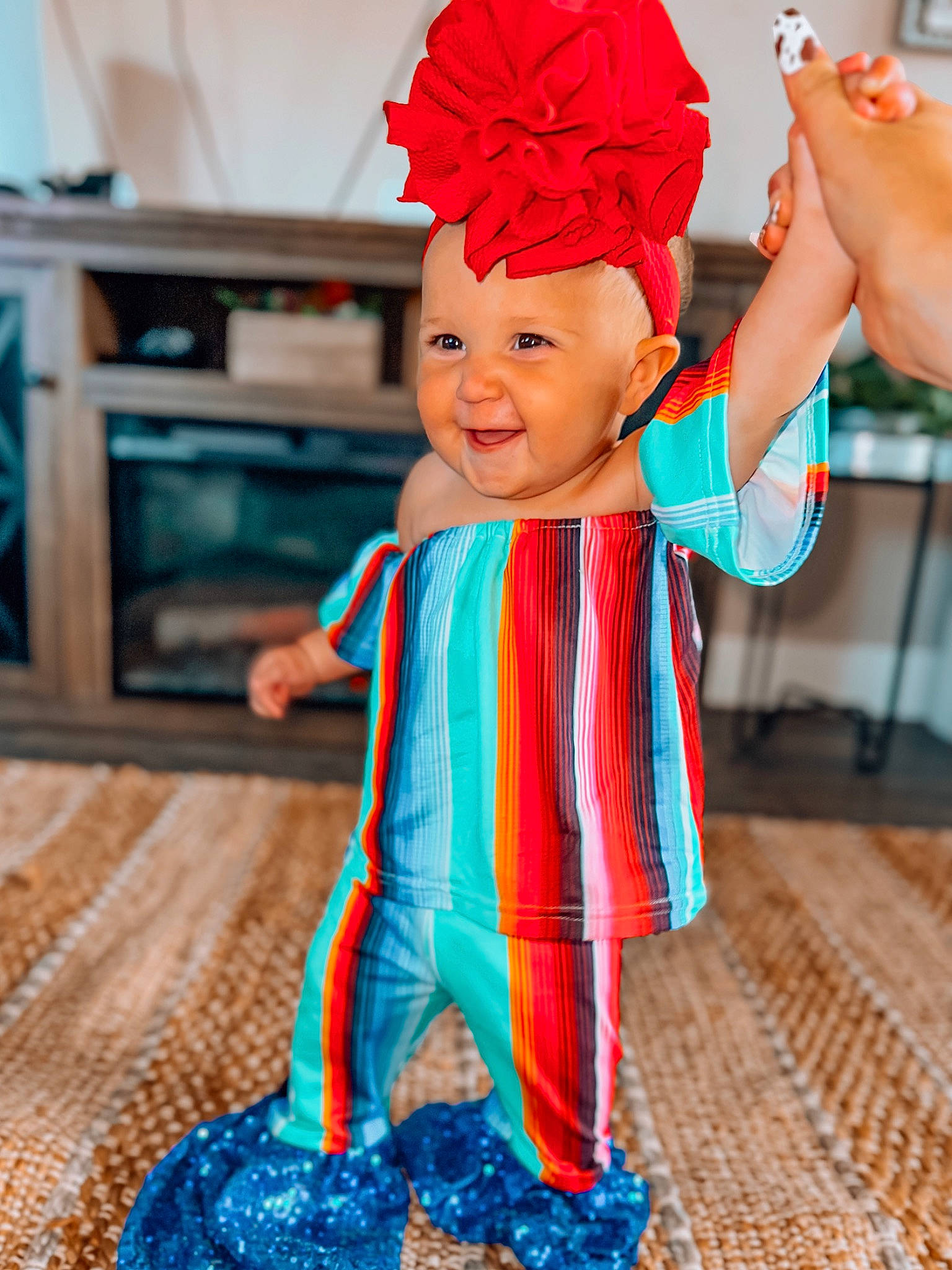 Adelaine is registered to the contest to win money with this photo: arm, baby, baby_toddler_clothing, blue, child, electric_blue, finger, flooring, gesture, hand, happy, headgear, headpiece, headwear, joy, orange, person, petal, pink, smile