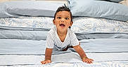Keshav joined the competition — help win amazing prizes! baby, child, crawling, smiling, happy, portrait, bed, bedroom, pillows, blanket, bedding, indoors, infant, face, eyes, open_mouth, striped_shirt, hands, 床, photography