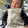 Zane is registered to the contest to win money with this photo: baby, infant, child, portrait, smiling, happy, lying_down, blanket, bed, bedding, sleepwear, gray_outfit, black_sleeves, cozy, indoors, close_up, face, hands, text_overlay, tuesday