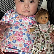 Melania joined the competition — help win amazing prizes! baby, child, doll, floral_clothing, patterned_blanket, portrait, indoor, cute, toy, childhood, person, face, hand, lying_down, colorful, soft_lighting, fabric, expression, young_child, playtime