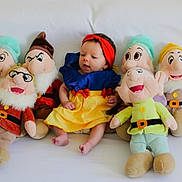 Hope a rejoint le concours — aidez-le/la à gagner de superbes lots ! baby, child, plush_toys, snow_white_costume, dwarfs, stuffed_animals, couch, white_background, costume, headband, sitting, soft_toys, colorful, indoor, cute, portrait, infant, smiling, playful, fairy_tale