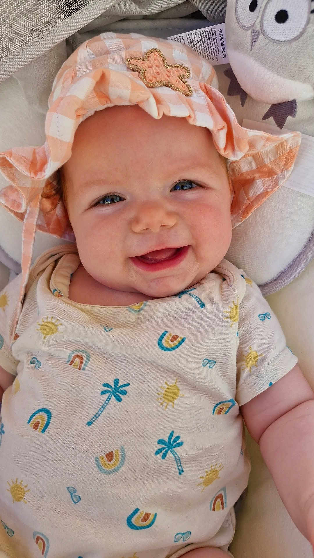 Hope participe au concours pour gagner de l'argent avec cette photo : baby, infant, smiling, hat, starfish, onesie, patterned_clothing, rainbow, sun, palm_tree, plush_toy, owl, cute, child, face, blue_eyes, cheerful, closeup, soft_toy, happy