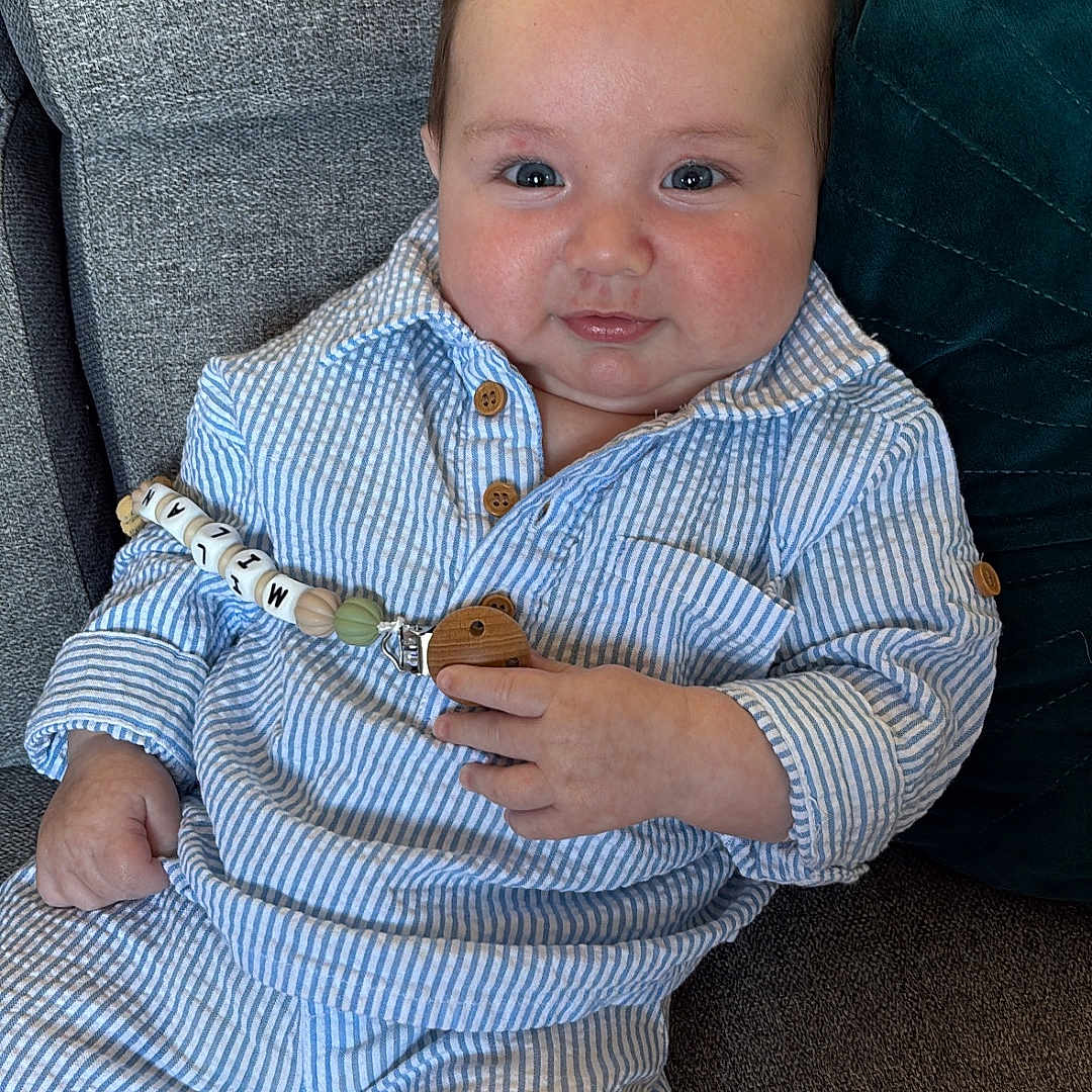 Milän participe au concours pour gagner de l'argent avec cette photo : baby, child, infant, couch, striped_clothing, blue_and_white, pacifier_clip, hair_style, mohawk, smiling, sitting, cute, indoors, plush, person, happy, small_hands, white_socks, wooden_toy, relaxed