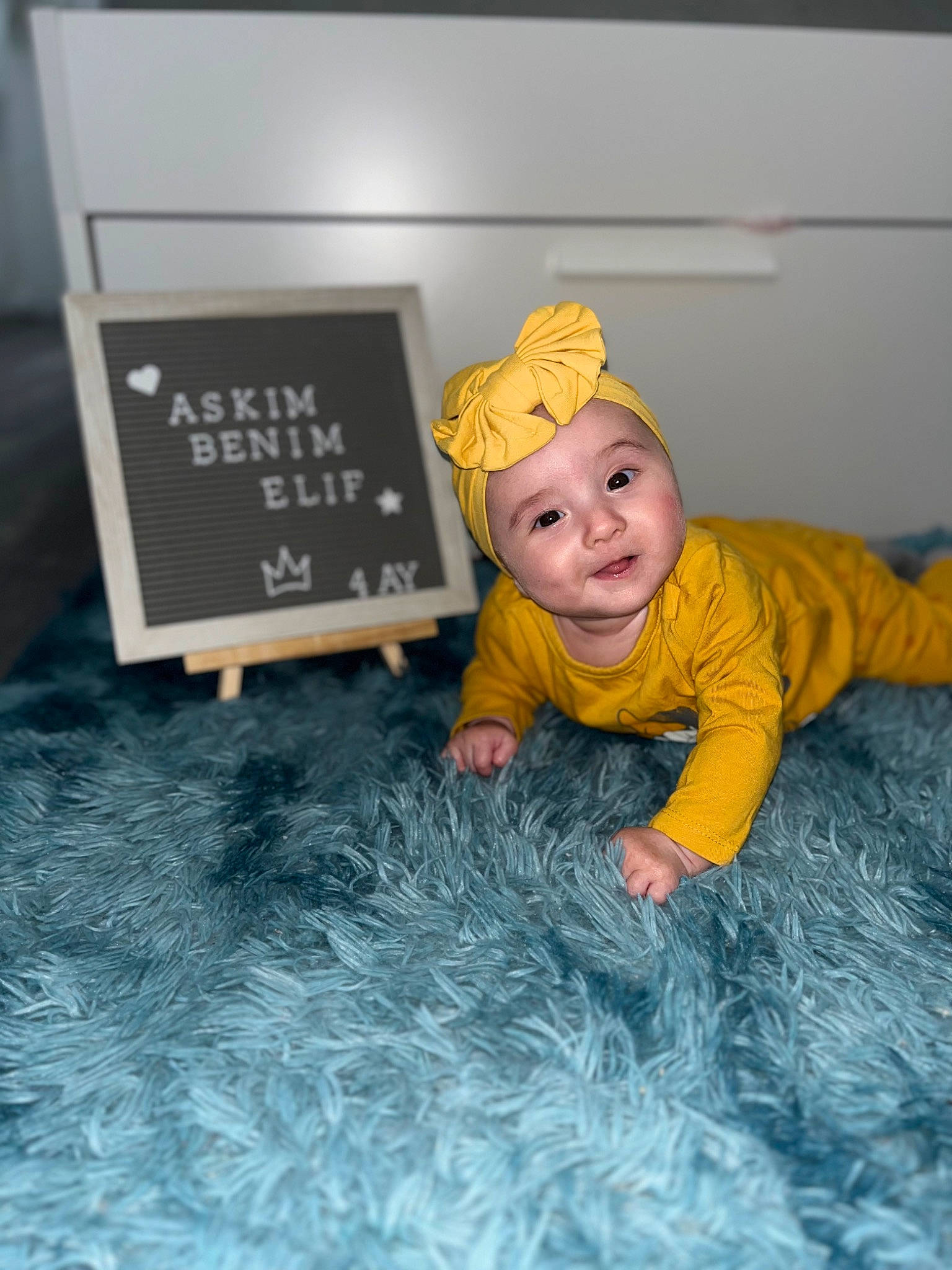 Elif a rejoint le concours — aidez-le/la à gagner de superbes lots ! baby, baby_toddler_clothing, blackboard, cap, chalk, child, crawling, flooring, font, fun, grass, happy, headwear, leisure, person, play, product, room, sitting, smile