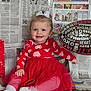 child, toddler, smile, red_dress, bow, headband, balloon, valentine_balloon, newspaper_background, heart_pattern, tulle_skirt, sitting, indoors, rosy_cheeks, cute, portrait, props, white_socks, happy, photography