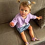 Eva a rejoint le concours — aidez-le/la à gagner de superbes lots ! toddler, child, pigtails, purple_cardigan, denim_skirt, sandals, couch, cushion, carpet, indoor, curious_expression, person, furniture, home, wall, pillow, baby_face_print, reaching_hand, seated, casual_clothing