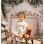 Eva participe au concours pour gagner de l'argent avec cette photo : toddler, child, teddy_bear, sled, holiday_decor, pine_garland, plush_toy, carpet, indoor, portrait, winter_clothing, white_dress, socks, wooden_furniture, christmas, decorations, cute, serious_expression, festive, cozy