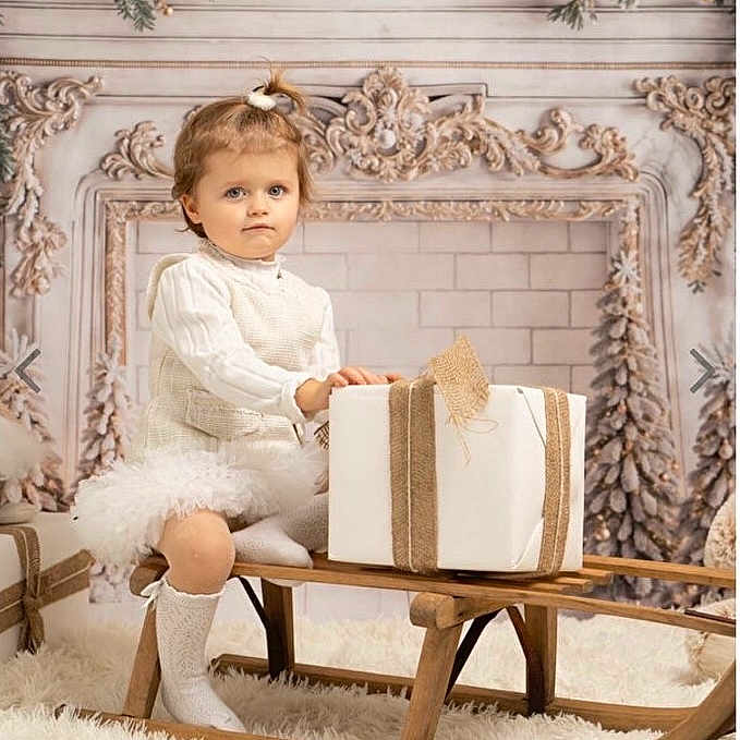 Eva participe au concours pour gagner de l'argent avec cette photo : carpet, child, cozy, cute, decorative_garland, expression, festive, gift, holiday_decor, indoor, knitwear, ornaments, portrait, present, sitting, sled, toddler, white_clothing, winter_theme, wooden_furniture