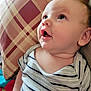 baby, child, striped_shirt, cushion, pattern, face, head, blue_eyes, skin, cheeks, mouth, expression, indoors, closeup, portrait, person, infant, curious, seated, soft_lighting