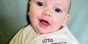 Cairo is registered to the contest to win money with this photo: baby, child, infant, smile, face, blue_eyes, cute, shirt, clothing, sitting, portrait, skin, happy, young, person, baby_fashion, closeup, head, indoors, soft_background
