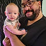 baby, man, child, person, indoor, portrait, glasses, beard, holding, curtains, smile, face, clothing, arm, hand, short_sleeves, expression, casual, family, intimate