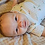 Cairo is registered to the contest to win money with this photo: baby, infant, smiling, face, eyes, onesie, clothing, patterned_bedding, vegetable_print, carrot, avocado, lying_down, curl_hair, skin, child, cute, portrait, indoors, soft_light, happy