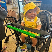 Anthony Gomez is registered to the contest to win money with this photo: baby, child, shopping_cart, yellow_hat, yellow_outfit, smile, grocery_store, person, footwear, can, bag, shopping, clothing, happy, indoor, retail, store_shelves, people, casual, infant