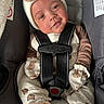 baby, child, car_seat, seat_belt, hat, knit_hat, clothing, mittens, footwear, plush_toy, cute, smile, portrait, indoor, infant, straps, safety, teddy_bear_pattern, person, closeup