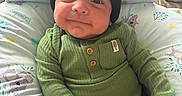 Santiago is registered to the contest to win money with this photo: baby, infant, child, green_onesie, black_beanie, smile, cushion, koala_print, pastel_colors, indoor, cute, chubby_cheeks, sitting, clothing, headwear, hand, face, soft_lighting, portrait, cozy