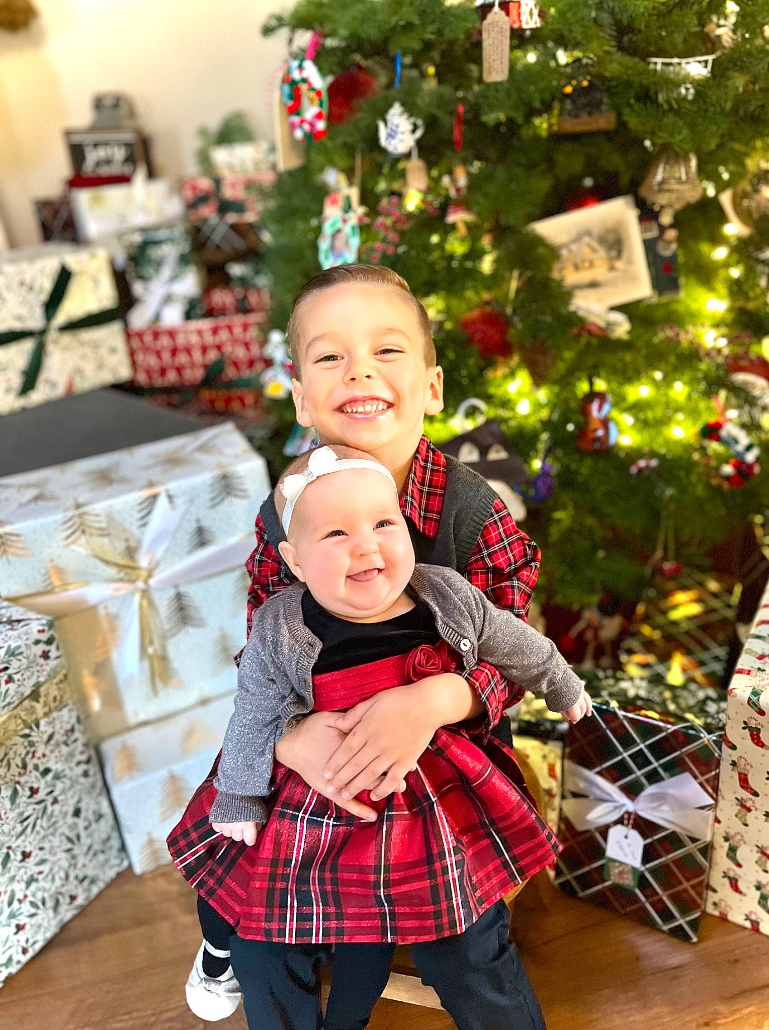 Emerson is registered to the contest to win money with this photo: baby, christmas, christmas_decoration, christmas_ornament, christmas_tree, event, face, facial_expression, fun, happy, head, headwear, holiday, human_body, joy, person, plaid, smile, snapshot, tartan