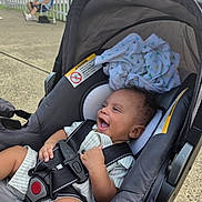 Jahmir is registered to the contest to win money with this photo: baby, car_seat, child, infant, smiling, happy, outdoor, person, seatbelt, clothing, fabric, blanket, tree, fence, pavement, sunlight, relaxation, park, casual, seated