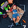 baby, denim_clothing, cardboard, tools, wrench, pliers, screwdriver, toy_drill, balloon, face_paint, bandana, asphalt, happy, child, playing, smiling, outdoor, sign, colorful, portrait
