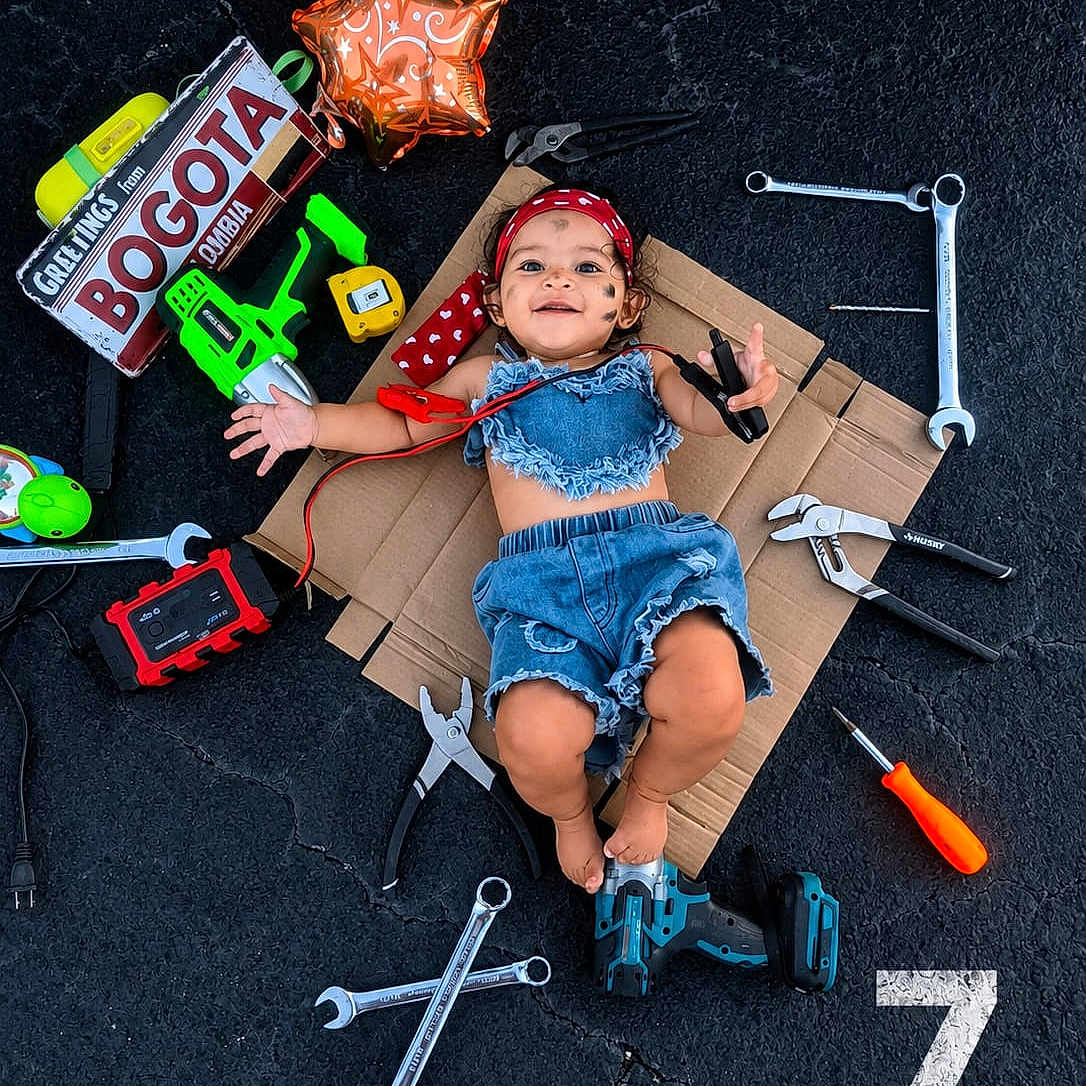 Anny Celeste joined the competition — help win amazing prizes! baby, denim_clothing, cardboard, tools, wrench, pliers, screwdriver, toy_drill, balloon, face_paint, bandana, asphalt, happy, child, playing, smiling, outdoor, sign, colorful, portrait