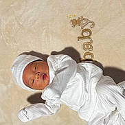Dennis is registered to the contest to win money with this photo: baby, newborn, infant, white_clothing, hat, blanket, lying_down, sleepy, cozy, soft_light, shadow, bedroom, cute, peaceful, portrait, child, human, indoors, resting, sleep