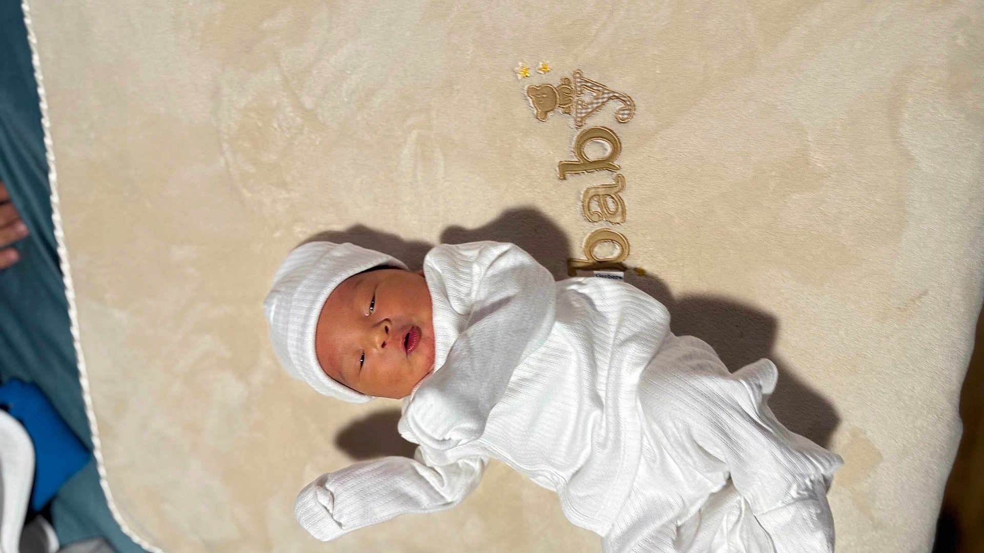 Dennis is registered to the contest to win money with this photo: baby, newborn, infant, white_clothing, hat, blanket, lying_down, sleepy, cozy, soft_light, shadow, bedroom, cute, peaceful, portrait, child, human, indoors, resting, sleep