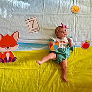 Lilia joined the competition — help win amazing prizes! baby, infant, child, toy, ball, headband, fox_illustration, sun_illustration, apple_illustration, blanket, green_outfit, white_lace, 7_months_card, colorful, playful, cute, curious, lying_down, indoors, portrait