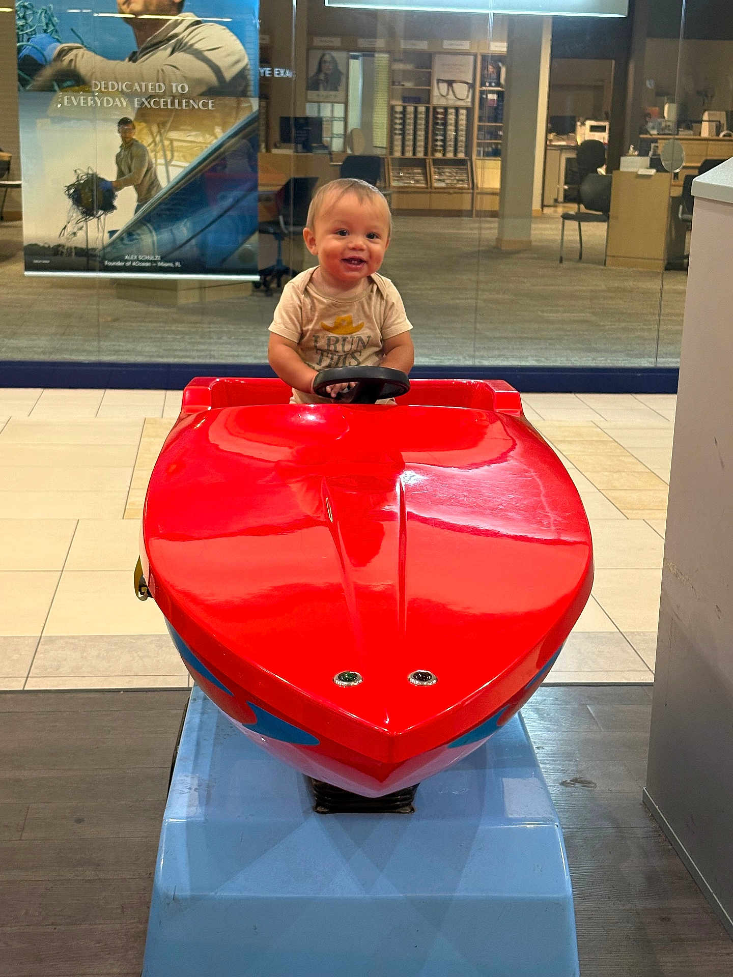 Aizen joined the competition — help win amazing prizes! toddler, child, red, toy, ride, boat, indoor, smile, steering_wheel, floor, glass_wall, chair, office, store, casual_clothing, happy, play, reflection, light, person