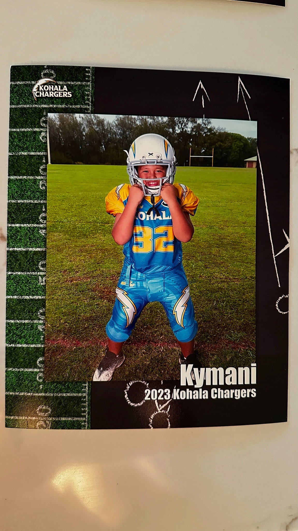 Kymani is registered to the contest to win money with this photo: advertising, astronaut, ball, font, grass, headwear, helmet, jersey, person, personal_protective_equipment, photo_caption, picture_frame, player, poster, rectangle, sleeve, sports_collectible, sports_equipment, sports_gear, sports_uniform