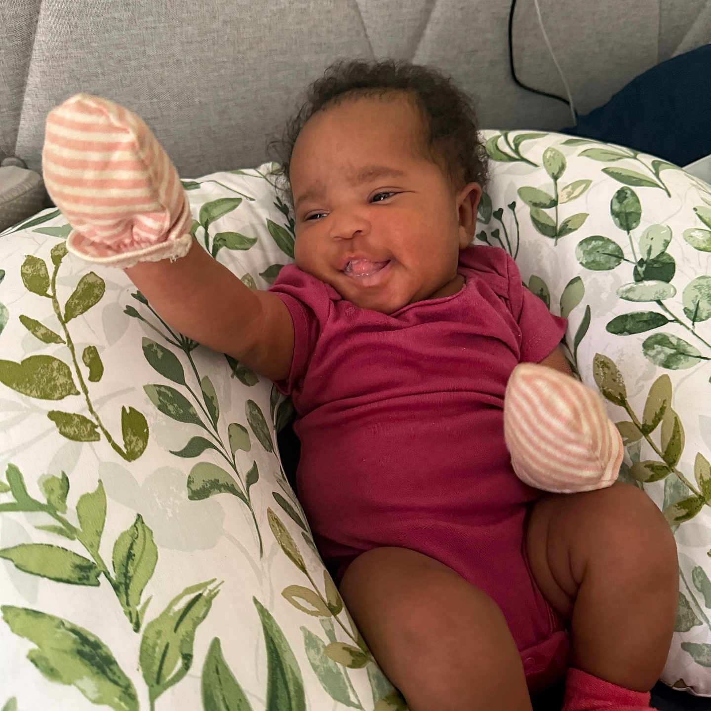 Autumn-Sahara is registered to the contest to win money with this photo: baby, child, cushion, cute, furniture, happy, headboard, home, indoor, infant, leaf_pattern, mittens, onesie, person, portrait, relaxing, smiling, socks, soft_fabric, young_child