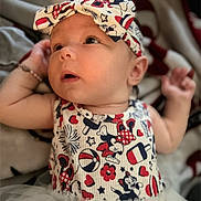 Shado is registered to the contest to win money with this photo: baby, infant, headband, clothing, patterned_clothing, cartoon_characters, red, white, blue, tutu, cute, portrait, child, smiling, face, hand, soft_fabric, blanket, indoors, young_child