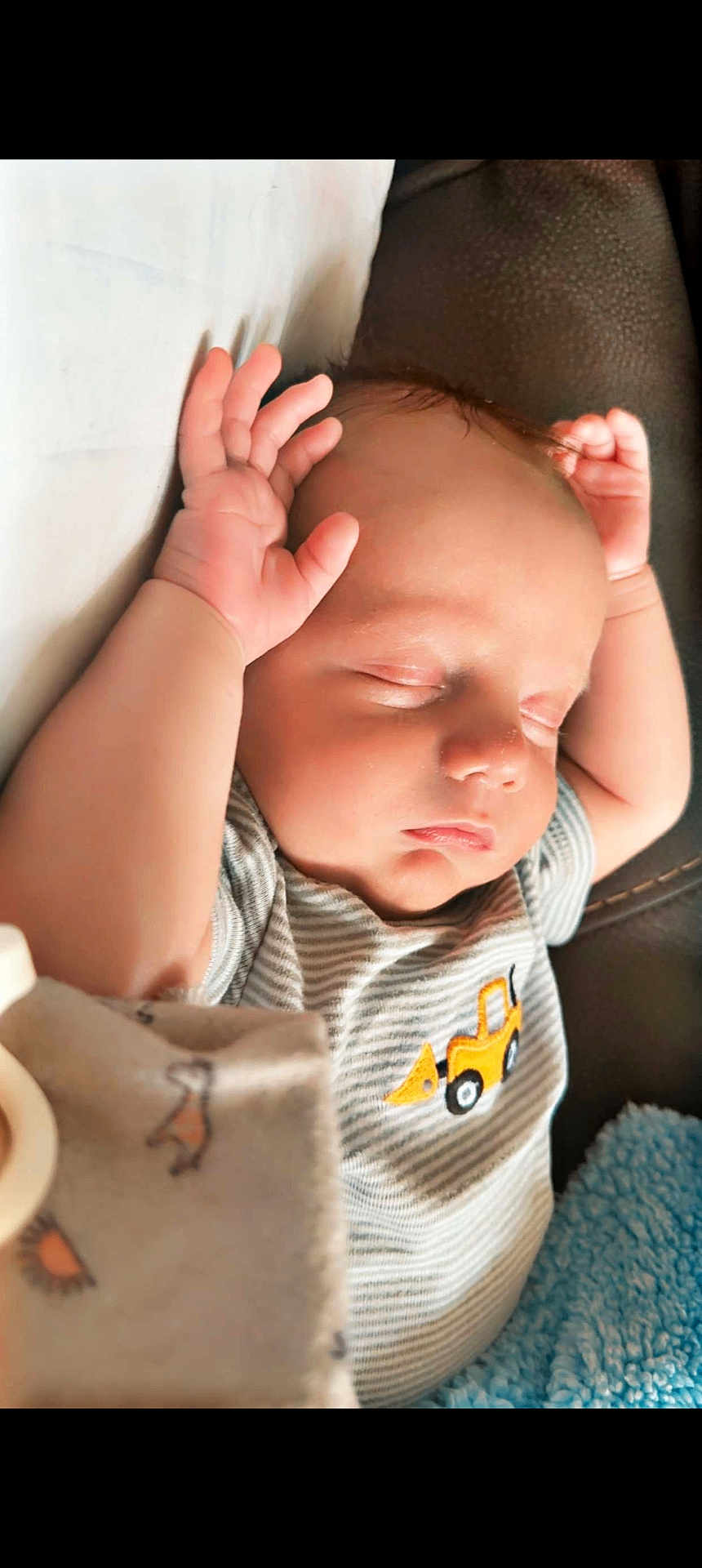 Soryn is registered to the contest to win money with this photo: arms_up, baby, blanket, casual_clothing, child, construction_vehicle, couch, cute, face, indoors, infant, newborn, peaceful, portrait, relaxation, resting, sleeping, soft_texture, striped_shirt, young_child
