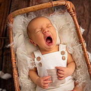 Kimi participe au concours pour gagner de l'argent avec cette photo : baby, yawning, basket, white_clothing, wooden_floor, fluffy_fabric, infant, sleepy, cute, newborn, hands, face, cozy, soft_texture, portrait, indoors, peaceful, relaxed, child, resting
