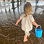 child, blonde_hair, ponytail, barefoot, bucket, water, shallow_water, ripples, pier, beach, sand, reflection, person, summer, outdoor, play, walking, casual_clothing, shorts, tshirt