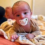 Noah a rejoint le concours — aidez-le/la à gagner de superbes lots ! baby, pacifier, blanket, infant, face, hand, bed, soft_focus, cute, child, lying_down, indoors, warm_colors, expression, person, skin, head, clothing, comfort, closeup