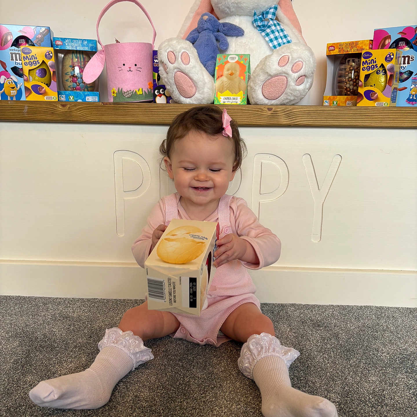 Poppy is registered to the contest to win money with this photo: accessories, bag, child, clothing, face, female, footwear, girl, head, hosiery, person, photography, plush, portrait, shelf, shoe, sitting, sock, toy, wood