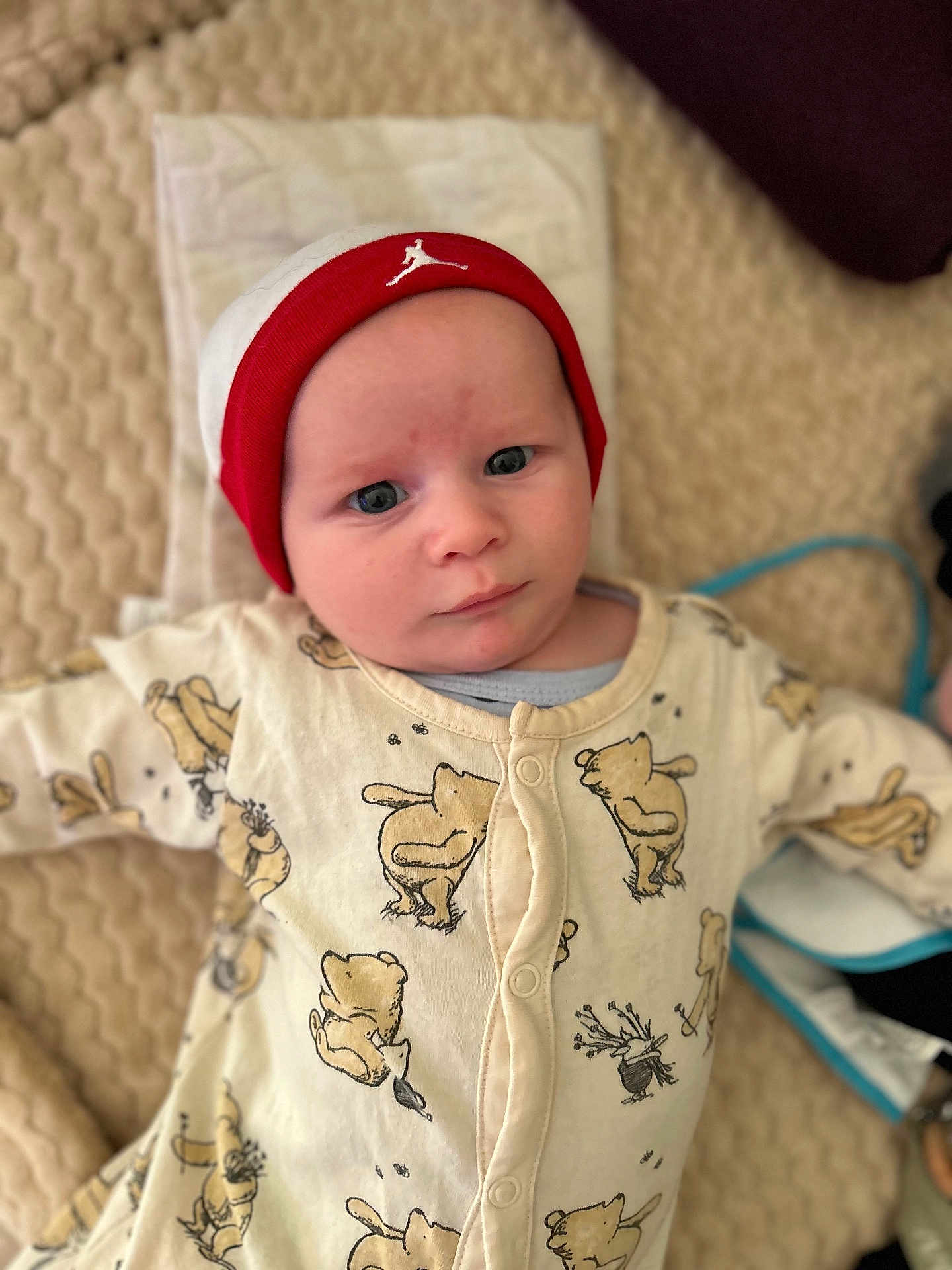 Owenn a rejoint le concours — aidez-le/la à gagner de superbes lots ! baby, infant, beanie, hat, onesie, baby_clothes, bear_pattern, blanket, lying_down, face, expression, indoor, cute, child, person, soft_lighting, texture, portrait, warm_colors, headwear