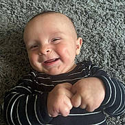 Wyatt is registered to the contest to win money with this photo: baby, infant, smiling, hands, carpet, striped_clothing, happy, cute, child, portrait, indoor, closeup, person, young, skin, head, face, expression, fingers, toddler