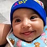 baby, smiling, blue_hat, bib, teddy_bear_pattern, cute, infant, child, face, happy, tongue_out, closeup, apparel, headwear, indoors, person, portrait, young_child, adorable, bright_eyes