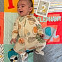 Kai is registered to the contest to win money with this photo: baby, infant, smiling, onesie, playmat, colorful, milestone_card, animal_illustrations, numbers, acorn_pattern, lying_down, happy, child, cute, indoor, soft_toys, feet, hand, head, face