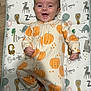 Kai joined the competition — help win amazing prizes! baby, infant, smiling, onesie, pumpkin, animal_print, floor_mat, happy, cute, lying_down, child, toddler, indoors, face, skin, hand, footwear, head, expression, playful