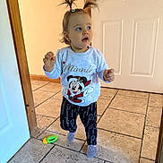 Milena is registered to the contest to win money with this photo: toddler, child, indoor, floor, toy, sweater, minnie_mouse, pants, socks, hair, pigtails, door, tile_floor, walking, cute, expression, person, clothing, home, light