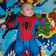 Zachariah is registered to the contest to win money with this photo: baby, child, spiderman_costume, superhero, marvel, blanket, colorful, infant, lying_down, cute, smiling, fist, cape, comic_characters, blue, red, green, yellow, portrait, indoor