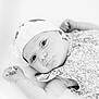 baby, infant, headband, floral, portrait, black_and_white, closeup, cute, child, newborn, lying_down, soft_light, patterned_clothing, expression, skin, face, hand, innocent, young, peaceful