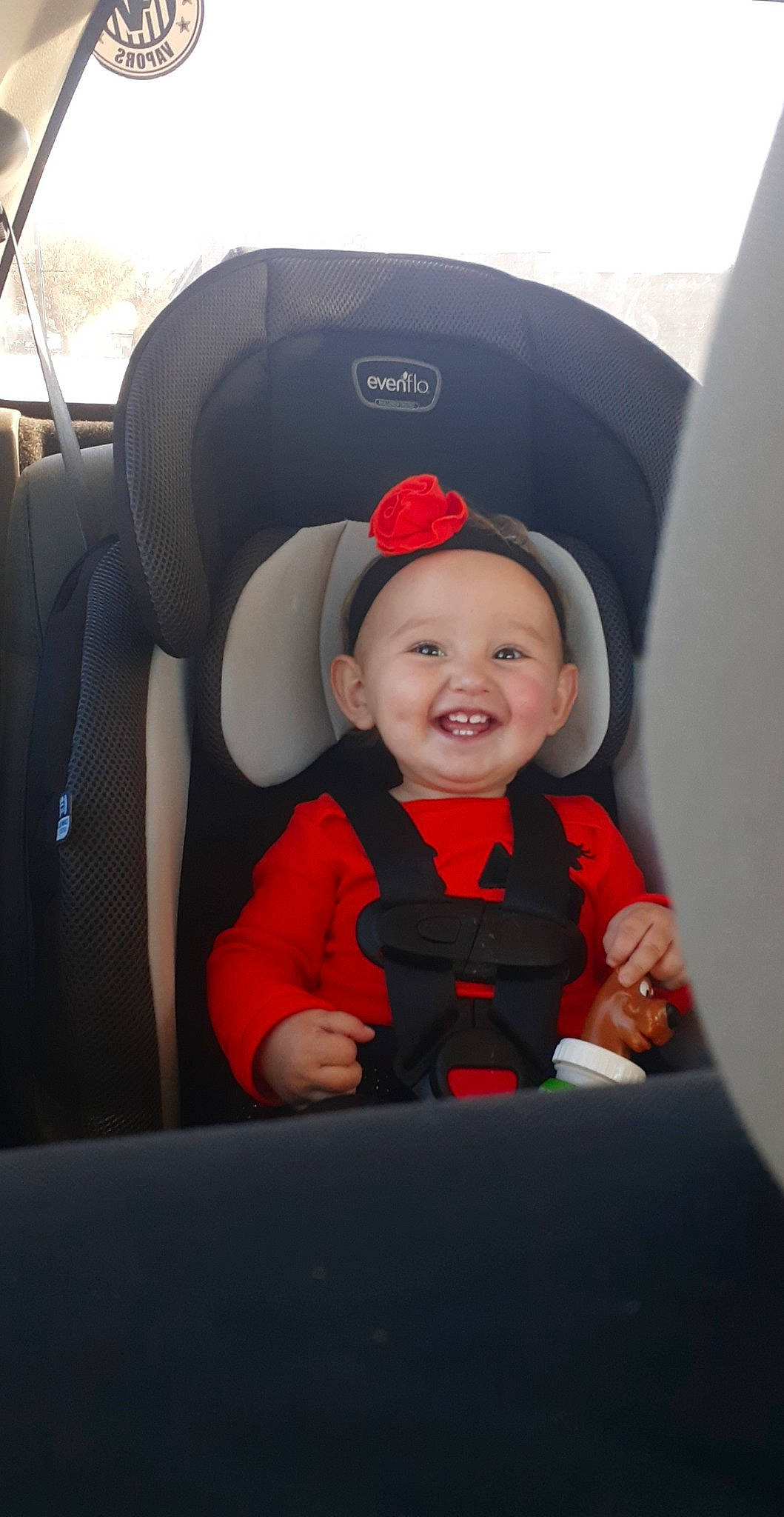 Aspen is registered to the contest to win money with this photo: baby, baby_in_car_seat, car_seat, child, fun, headwear, joy, person, photography, red, smile, toddler, vacation, vehicle