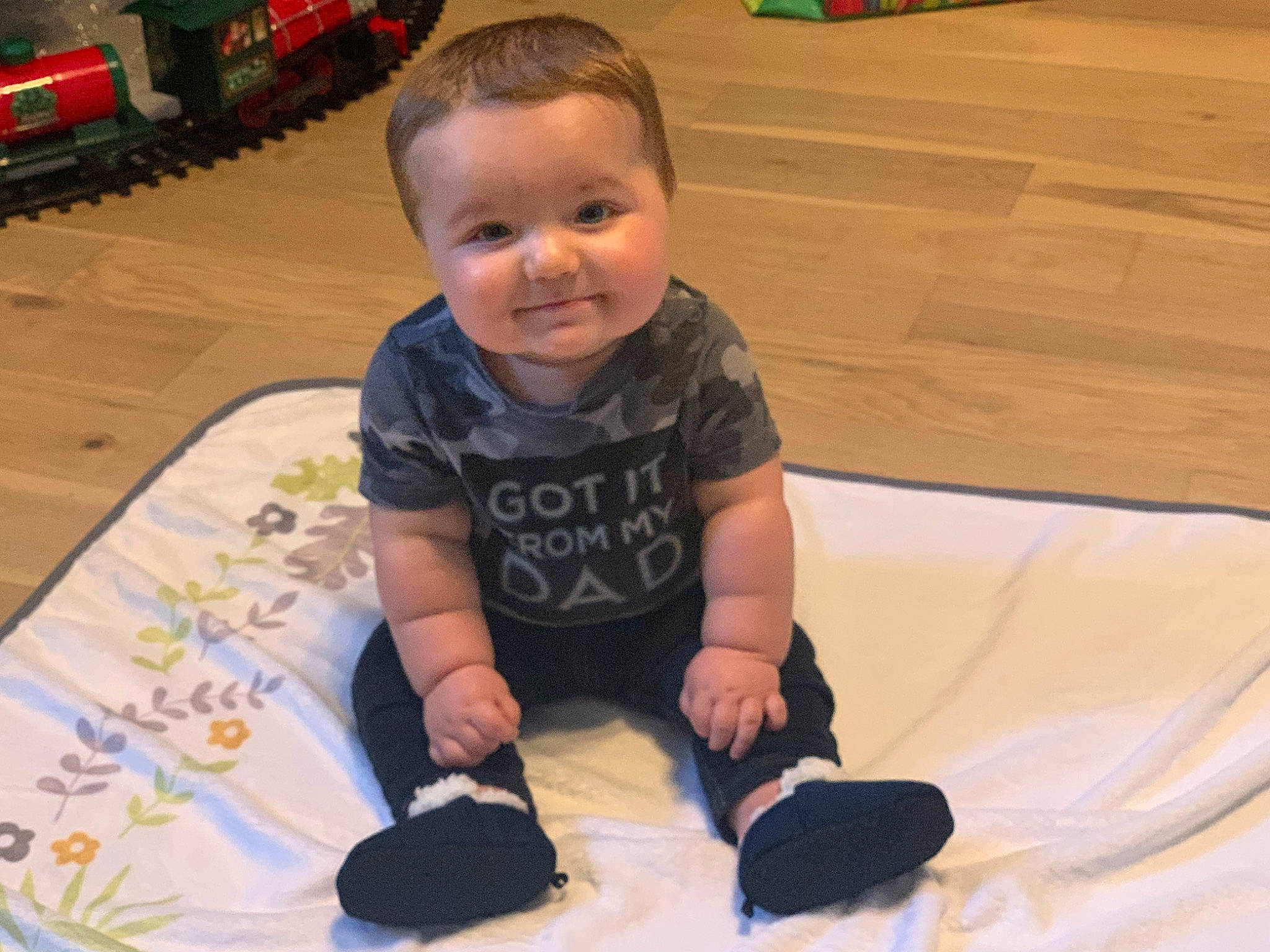 Brock is registered to the contest to win money with this photo: arm, baby, baby_toddler_clothing, cheek, child, comfort, flooring, fun, happy, hardwood, leg, leisure, linens, person, sitting, skin, sleeve, smile, t_shirt, toddler