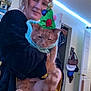 Dewey is registered to the contest to win money with this photo: person, cat, orange_cat, sweater, christmas_hat, indoor, room, door, bags, led_lights, holding, pet, animal, feline, holiday, festive, costume, smile, casual, home